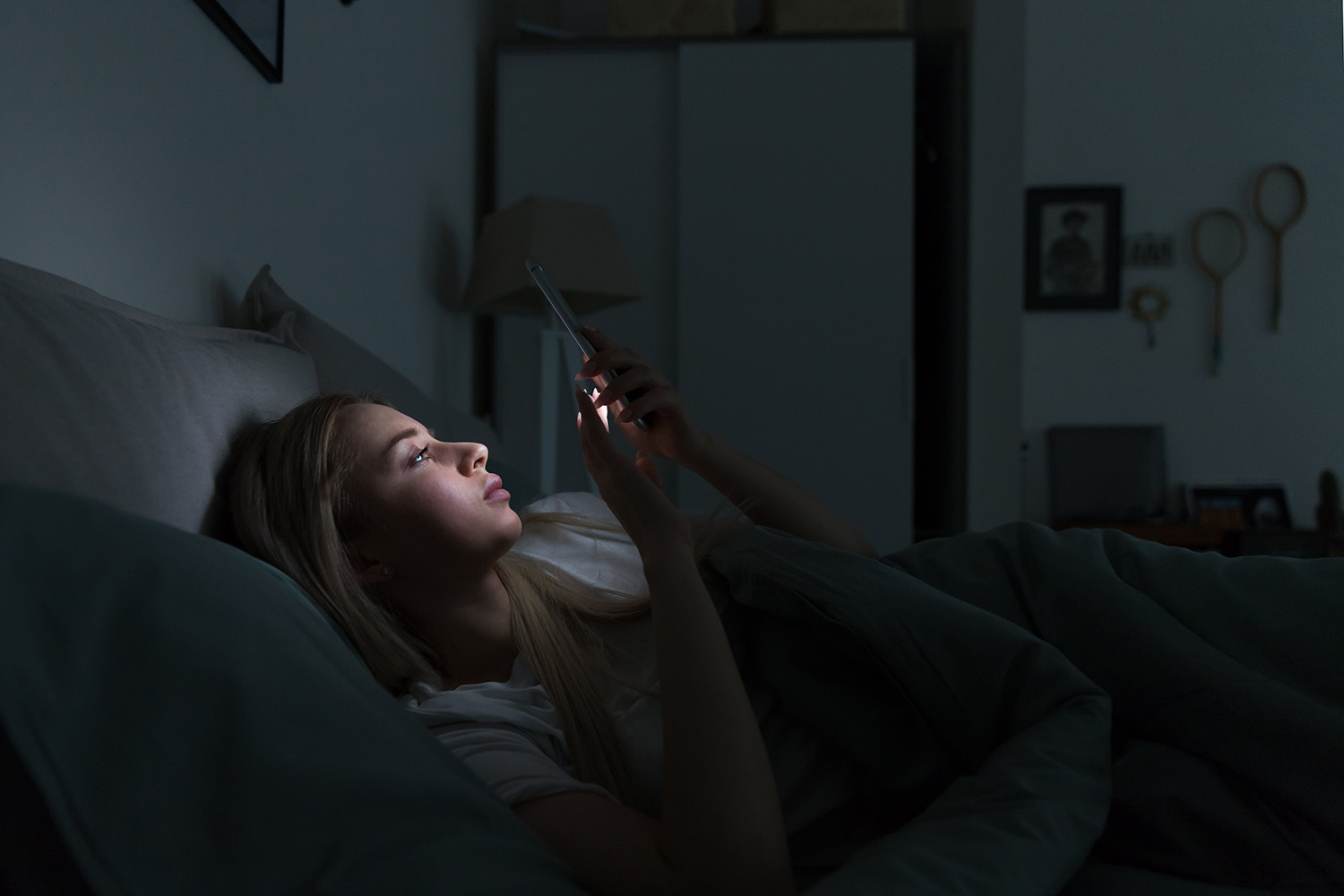 Vrouw kijkt op telefoon in bed